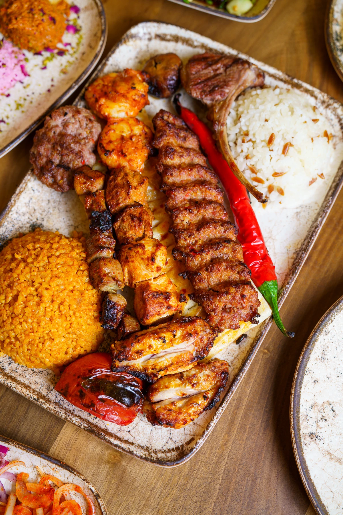 A mixed grill platter with meze and bread on the table