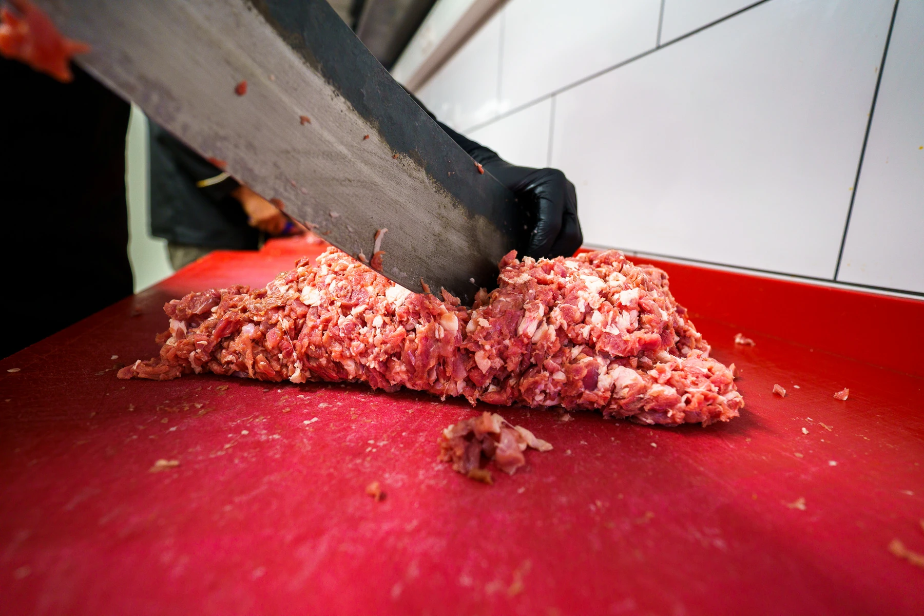 Meat being prepared by hand with a large knife