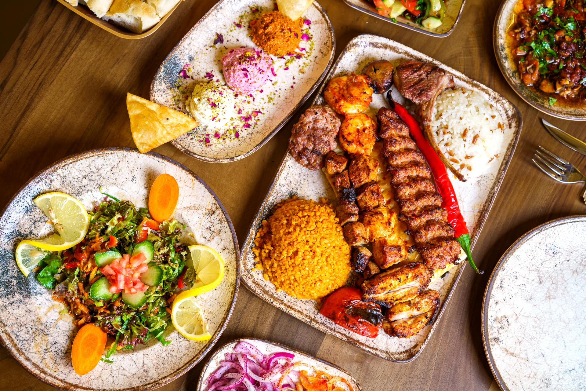 Grillgerichte mit Reis, Salat und Meze auf einem gedeckten Tisch